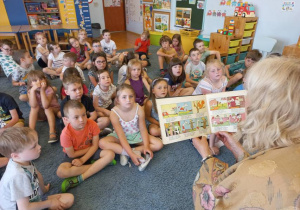 Aktorka czyta dzieciom opowiadania – dzieci siedzą na dywanie.